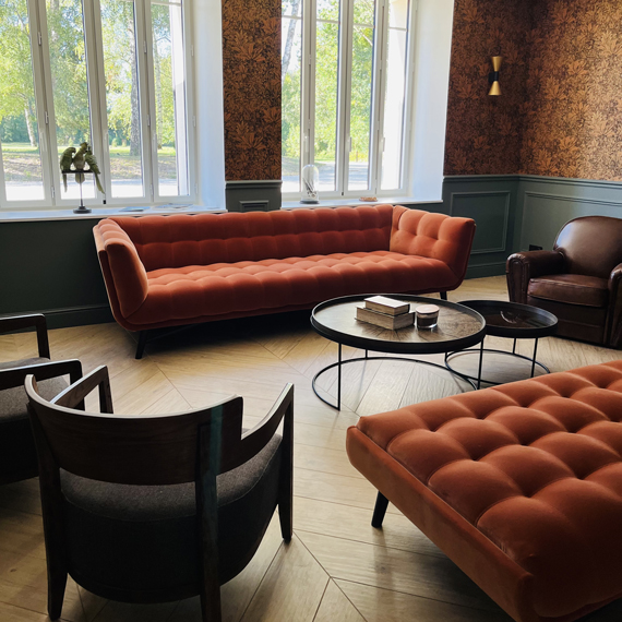 Salon avec sièges et canapés dans la salle de réception du somaine de la verrerie de St Gond